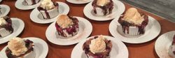 table full of mixed berry cobbler in ceramic bowls topped with ice cream