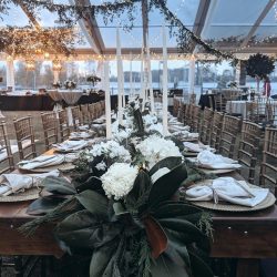 long table set with white napkins, candles, flowers and magnolia leaf greenery