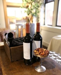 two bottles of red wine and bar nuts on bar